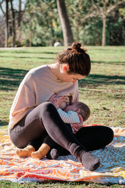 istock Young woman breastfeeding her son outdoors in a public park 1367568440