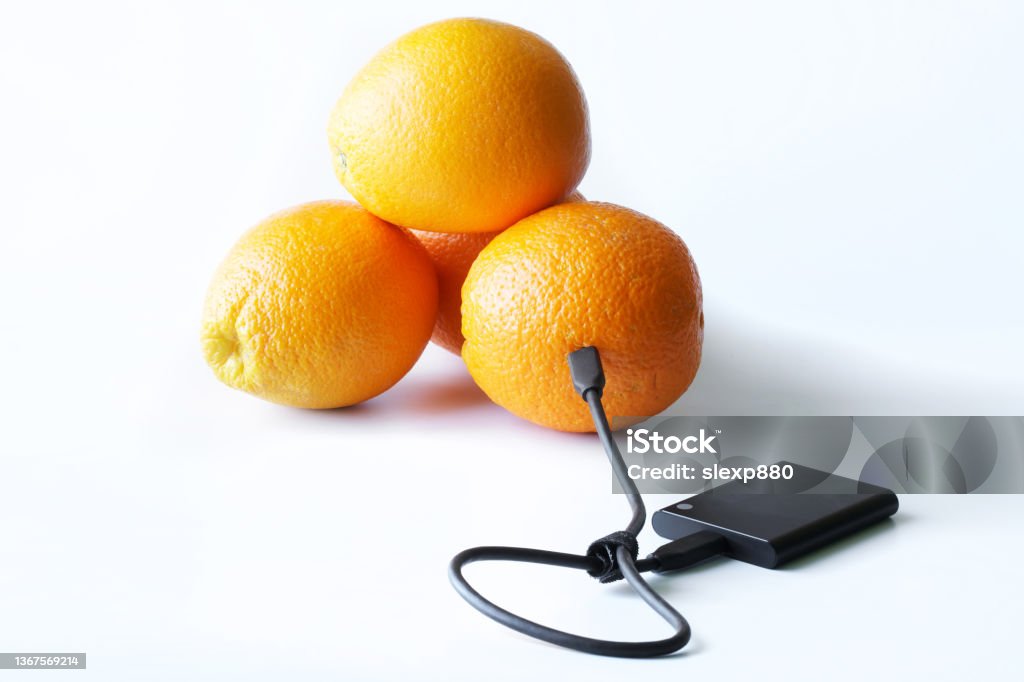 The external SSD is wired to fresh oranges. The concept of green technologies and data storage in the blockchain. The concept of expanding the hosting space. Solid State Drive The external SSD is wired to fresh oranges. The concept of green technologies and data storage in the blockchain. The concept of expanding the hosting space. Solid State Drive. White background USB Port Stock Photo