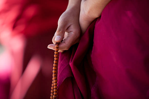 A monk in traditional clothing holding prayer beads stock photo