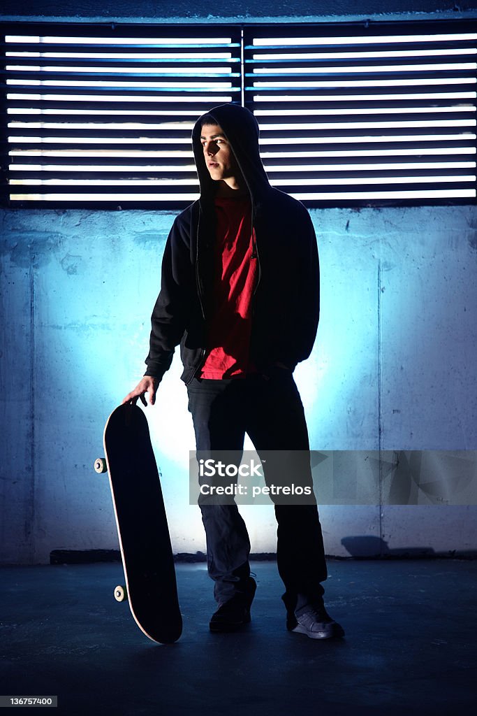 Adolescente com um skate no Fundo azul escuro - Foto de stock de Noite royalty-free