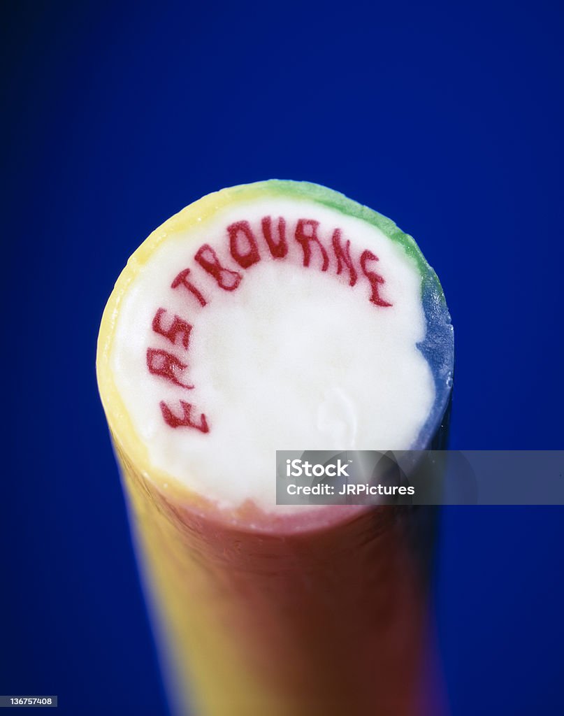 colourful stick of rock from eastbourne on vibrant blue background a colourful stick of rock from the seaside resort of eastbourne in the uk on vibrant blue background Stick of Hard Candy Stock Photo
