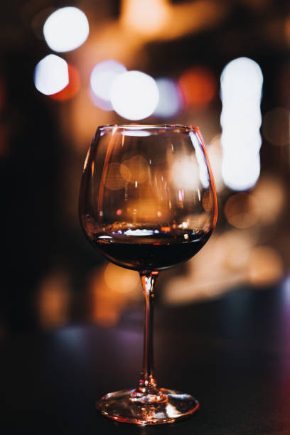 istock Red wine in a glass goblet against blurred evening lights. Vertical 1367574307