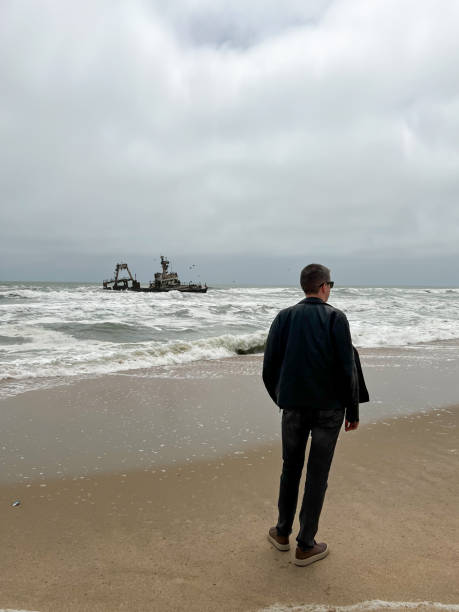 istock Sunken trawler, shipwreck. Ship Zeila at Skeleton Coast Namibia. Man stands 1367575328