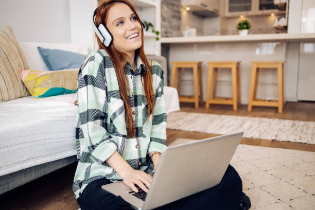 istock Beautiful girl using headphones and laptop while surfing the net 1367581327