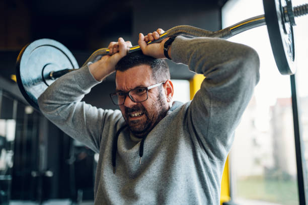 istock Middle aged man lifting barbell in the gym 1367581597