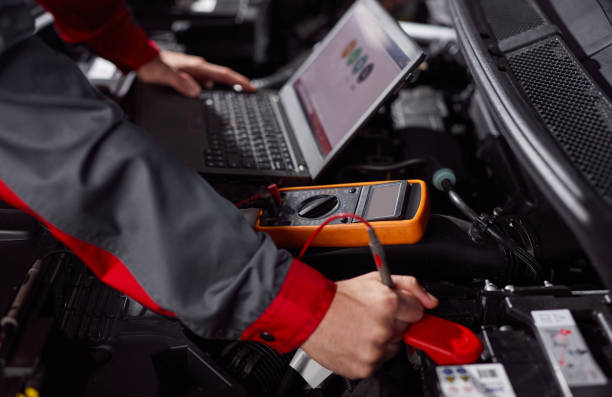 istock Anonymous repairman doing car diagnostic with multimeter and netbook 1367581808