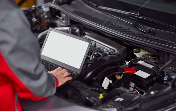 Mechanic using laptop during car engine diagnostic stock photo
