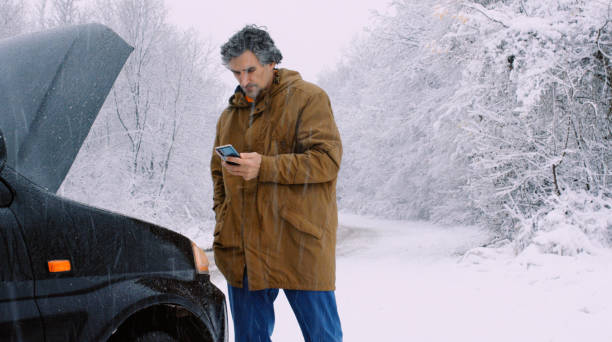 istock Man with car issues on winter road, phone calling for help. 1367582857