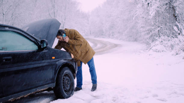Man with car issues on winter road, phone calling for help. stock photo
