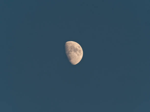 White half moon isolated on dark blue sky, telephoto image.