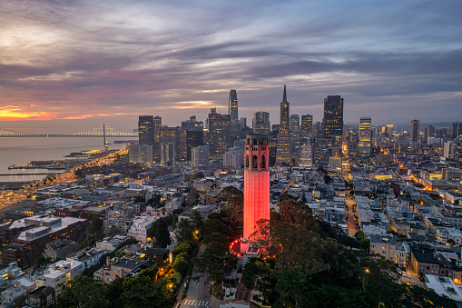 An aerial view of Coit Tower and the San Francisco Skyline in the distance with a dramatic and vibrant sky.