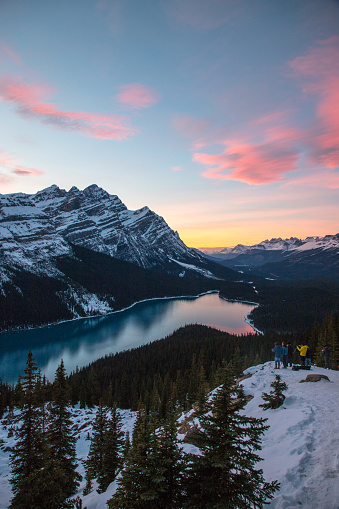 A vertical landscape image shows tourists enjoying the sunset at Peyto Lake in Banff National Park, Alberta, Canada.