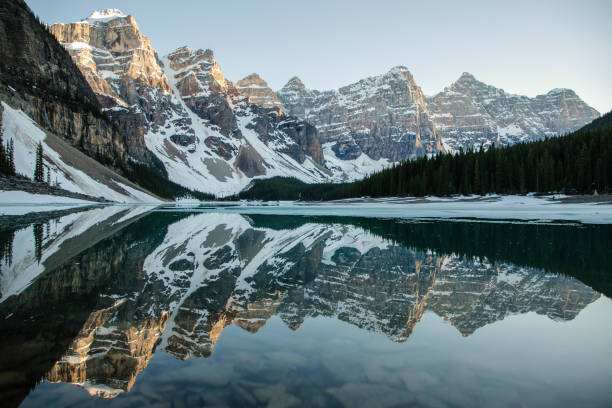 Symmetry at Moraine Lake, Banff National Park, Alberta, Canada. A horizontal landscape photo of symmetrical reflections in the waters of Moraine Lake in Banff National Park, Alberta, Canada. Taken just before sunset, allowing for alpenglow on the mountain peaks. reflection lake stock pictures, royalty-free photos & images