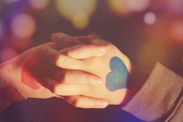 istock Close up of two painted hands holding, in blue and in red colors. 1367589607