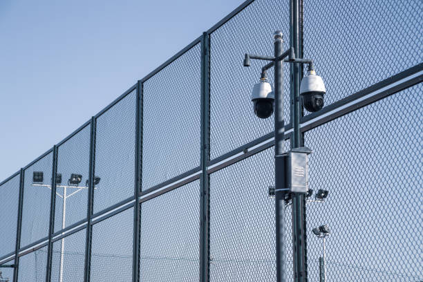 modernas cámaras de video de vigilancia, malla metálica e iluminación - safety fence fotografías e imágenes de stock