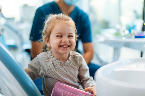 Smiling young girl sitting in a dental chair in her dentists office