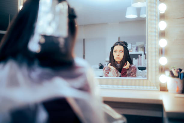 Funny Woman Looking in the Mirror at Hair Salon Worried beauty center customer unhappy about the makeover about to happen angry hairstylist stock pictures, royalty-free photos & images
