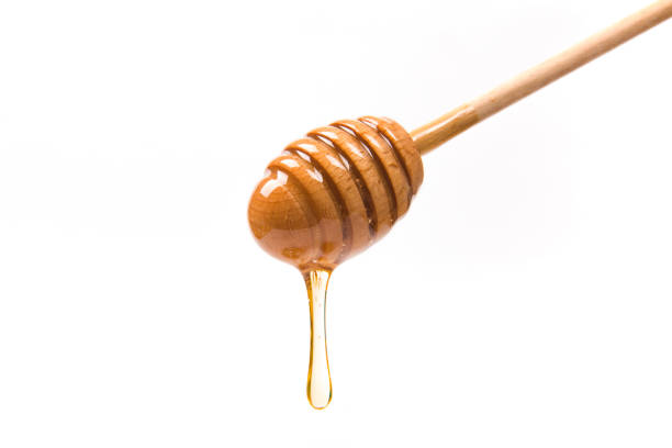 istock Honey dripping from honey dipper on white background 1367600196