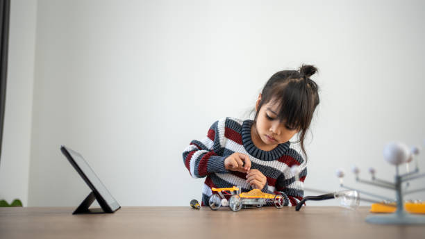 Asian girls enjoy making and fixing electrical robot car and learning online tutor training course stock photo