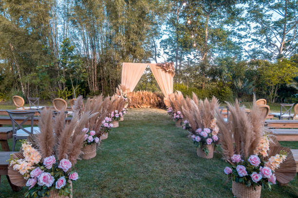 istock A rustic garden wedding setup, the main aisle lined with baskets with pampas leaves and pastel pink roses. Trees in the background. 1367623724