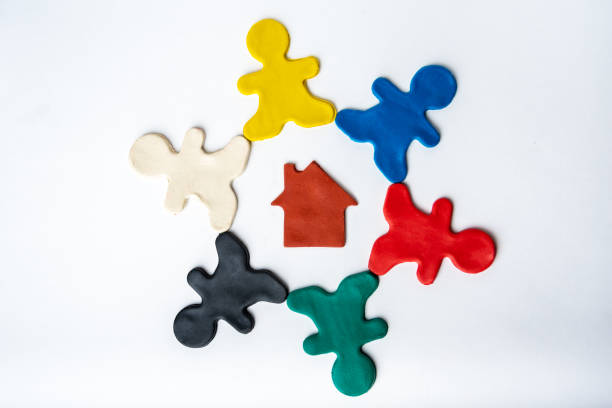 brown plasticine house in the center of multi-colored bright plasticine men in a circle isolated on a white background - childs play clay small men team imagens e fotografias de stock