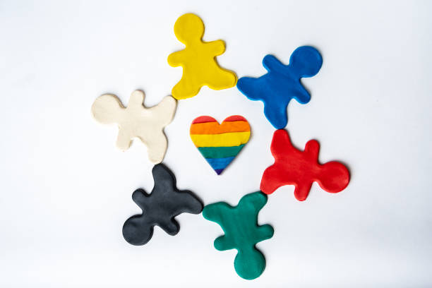 forma de corazón de arco iris en el centro y personas de plastilina brillante multicolor en un círculo aislado sobre fondo blanco - childs play clay small men team fotografías e imágenes de stock