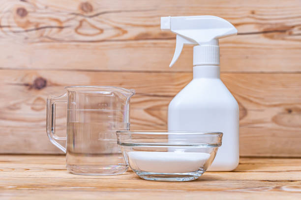 Making baking paste.　Baking soda in acontainer and a measuring cup and a spray bottle on wooden background. stock photo