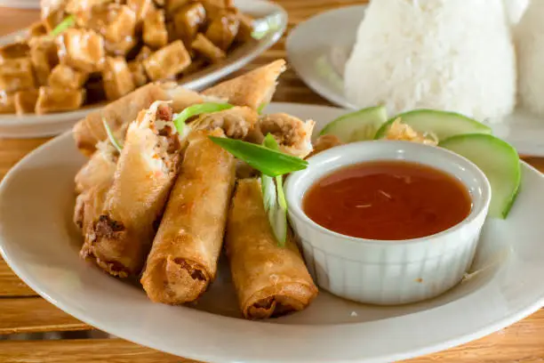 Lumpiang Shanghai, a Filipino egg roll, with Sizzling tofu and a cup of rice at the back. Philippine cuisine.