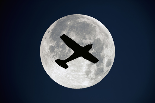 Airplane flying over the full Moon disk.