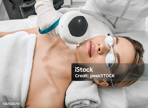 istock Photorejuvenation of a woman's face using intense pulsed light IPL with a beautician in a cosmetology salon for rosacea treatment, removing brown spots and vascular mesh 1367625701