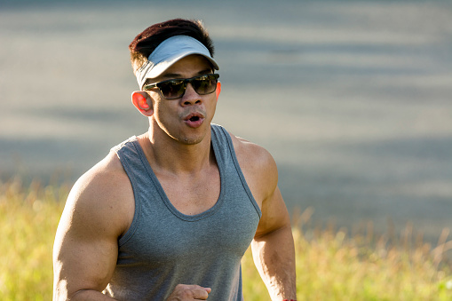 Closeup of an athletic man breathing hard during an intense fartlek running session. Aerobic exercise and cardio outdoors.