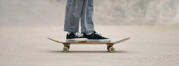 Photo of Foot of skateboarder standing on the skateboard on the city street