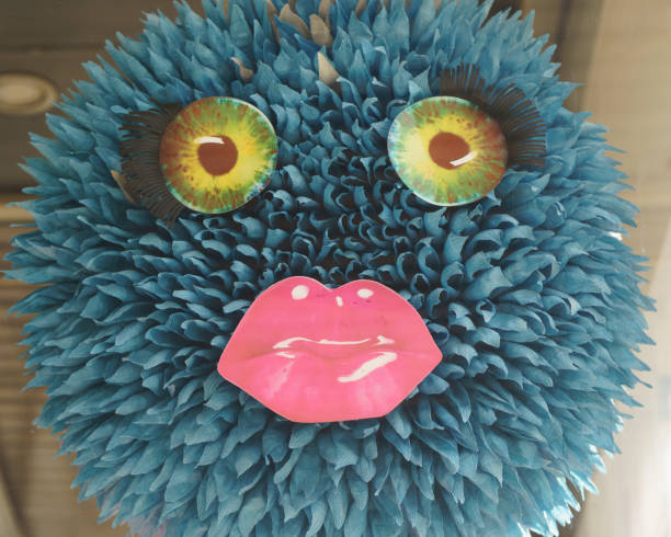 Beautiful cartoon female face with big eyes, long black eyelashes and lips painted with pink lipstick. Ironic portrayal of artsy female unnatural beauty. Close up photography, modern abstract  portrait