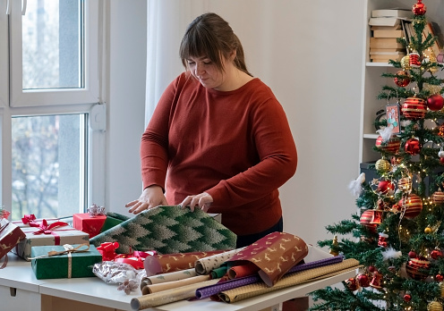 Young woman preparing Christmas presents at home.
