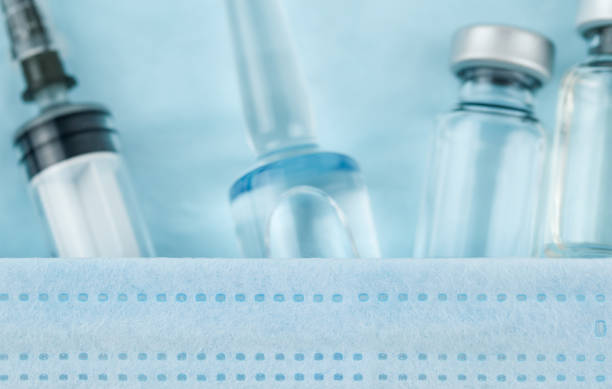 istock Syringe for injection, protective mask and Vaccine  on a blue background. 1367637049