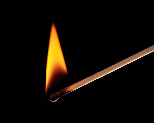 Burning match isolated on black background. Close-up.