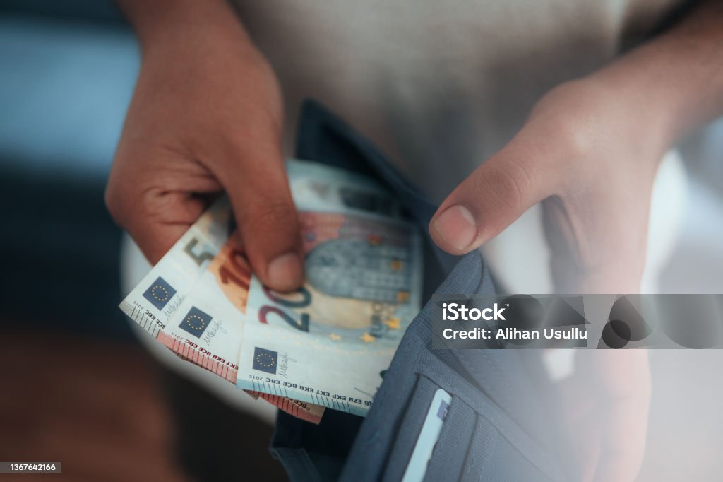 Young man holding in hands wallet with euro money Young man holding in hands wallet with euro money. Horizontal composition. European Union Currency Stock Photo