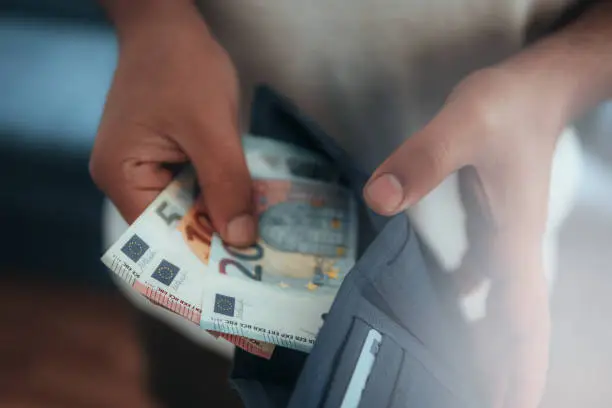 Young man holding in hands wallet with euro money. Horizontal composition.