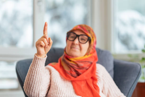 Portrait of an old Muslim woman with her walking stick at home wearing traditional hijab, looking away. High quality photo