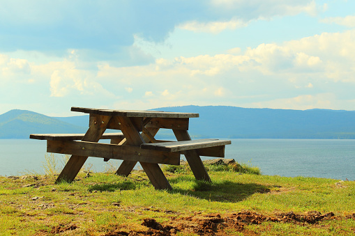 Wooden table and benches on the hill in front of the lake. Beautiful landscape. Background.