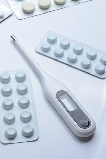 istock tablets in a package and a white electronic thermometer on a white surface close-up. 1367647370
