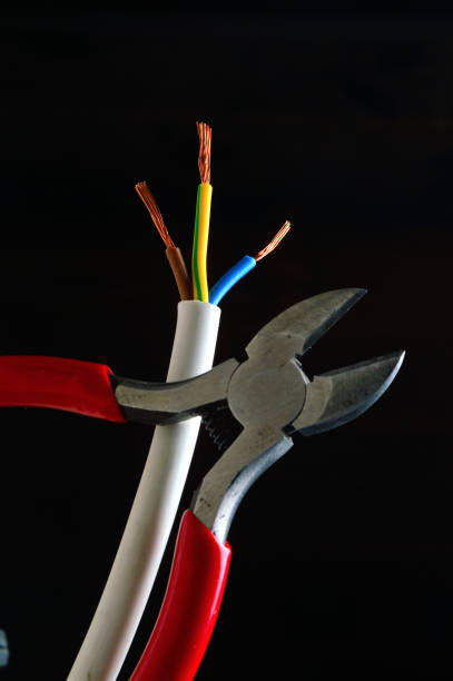 stripped, three-core wire and wire cutters on a dark background. dark background close-up