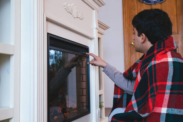 Young man at home starting the electric fireplace