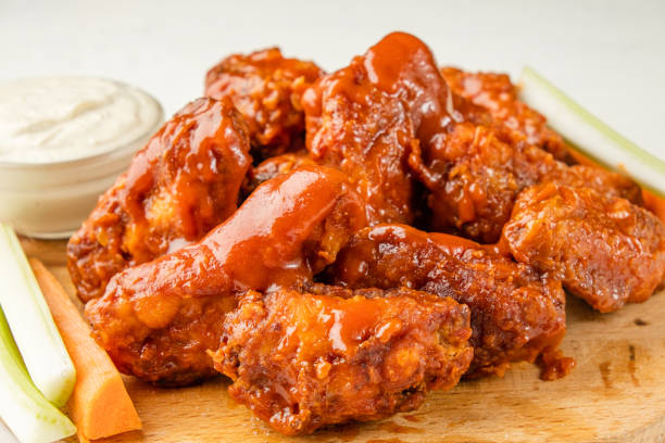 istock Fried buffalo chicken wings served with chopped vegetables on a white table. 1367647824