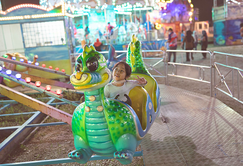 Adorable asian girl having fun at a local amusement park at night time during Covid-19 pandemic, in Malaysia.