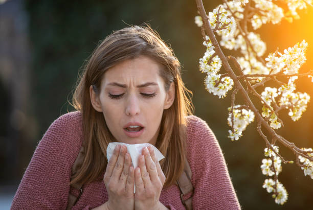 istock Girl sneezing in front of blooming tree in spring 1367653565