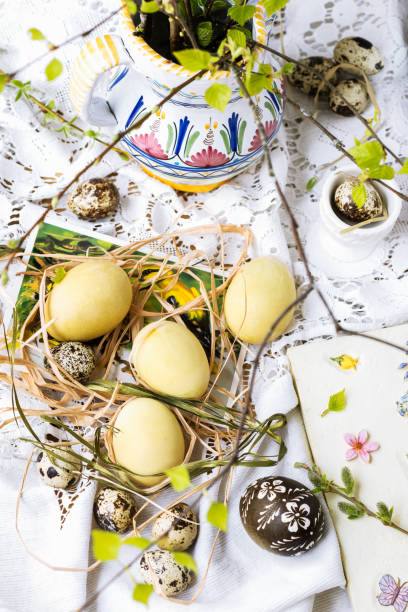 istock Traditional Easter eggs colored  with chamomile flowers in yellow color, quail eggs, bouquet of branches  with unfolded leaves on the festive Easter table 1367653779