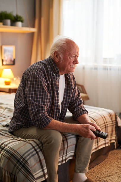 istock Old man enjoying his favourite programme on TV 1367657179