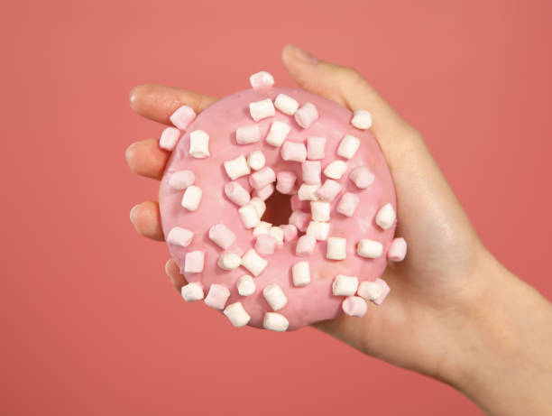 istock pink donut with marshmallow in hand 1367658284