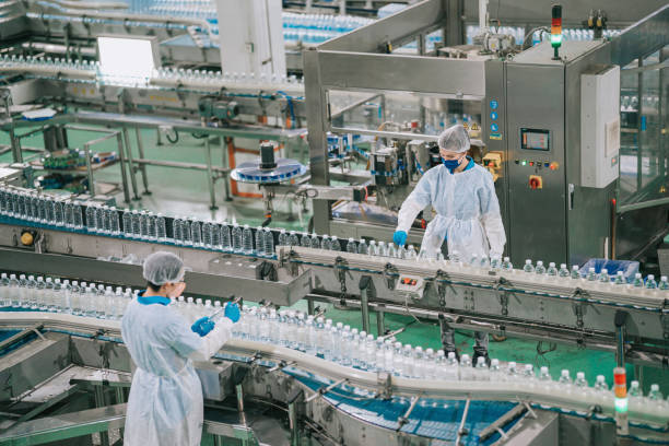 2 trabajadores de la línea de producción de la fábrica de agua potable china asiática con epp examinando la botella de agua que funciona en la rutina diaria - food service industry fotografías e imágenes de stock